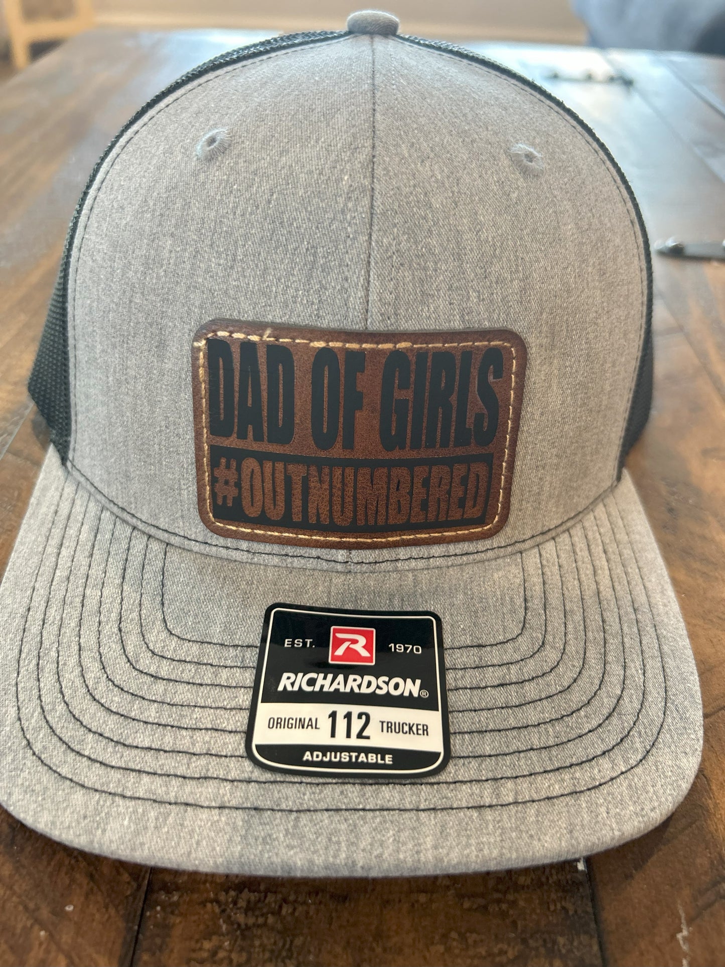 "Dad of Girls #OUTNUMBERED" on Rustic Leather Patch Trucker Hat